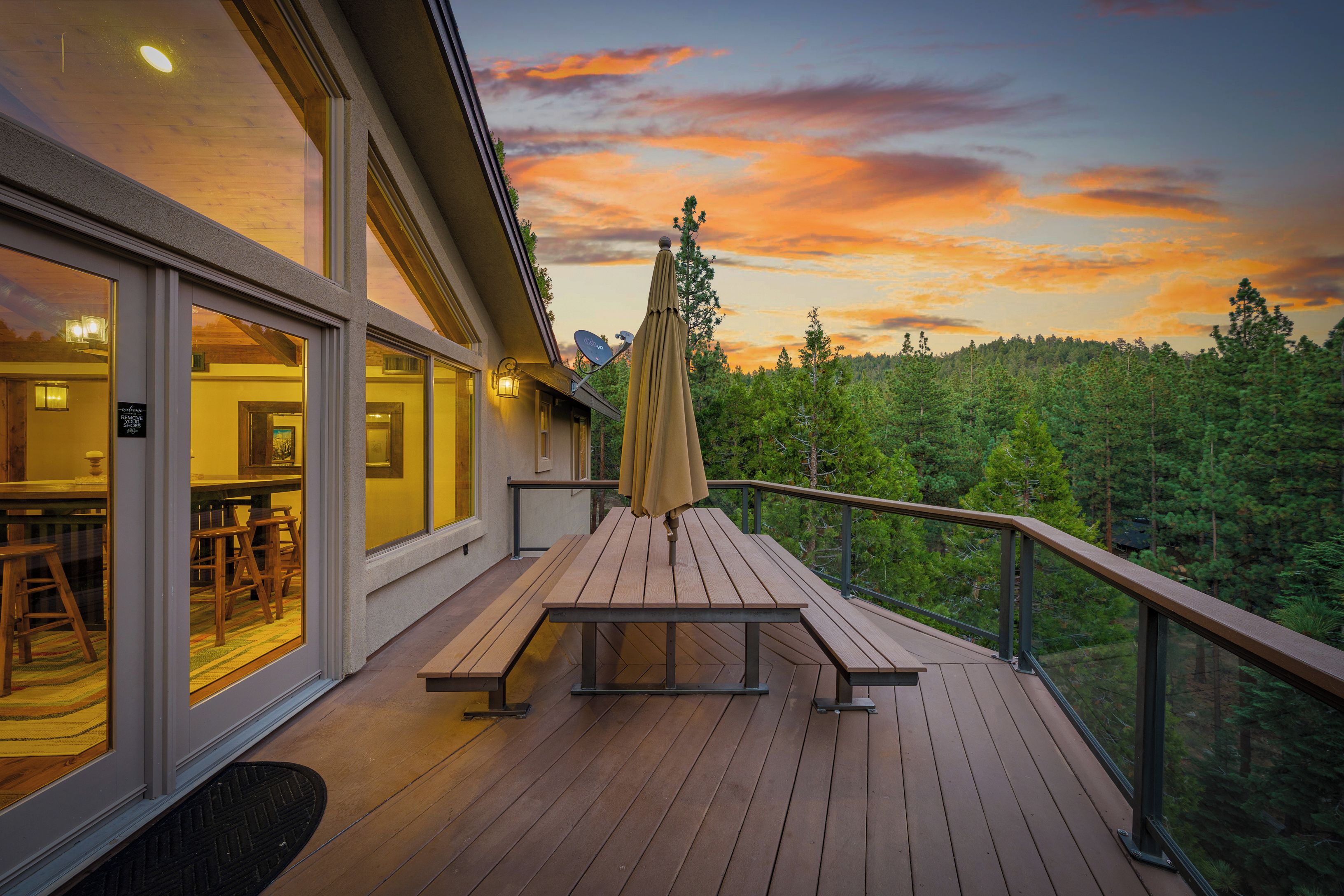 A wooden deck with a table and benches, overlooking a forested area.