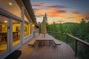 A wooden deck with a table and benches, overlooking a forested area.