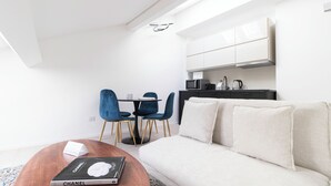 Ein modernes Wohnzimmer mit einer Couch, einem Couchtisch mit einem Buch und zwei blauen Sesseln.