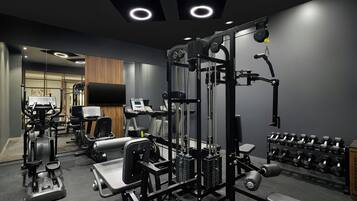 A gym with various exercise equipment, including a cable machine, treadmills, and dumbbells.