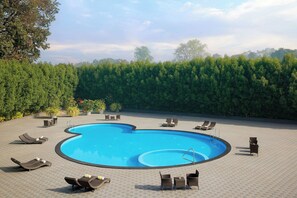 Une piscine avec des chaises longues et une terrasse dallée.