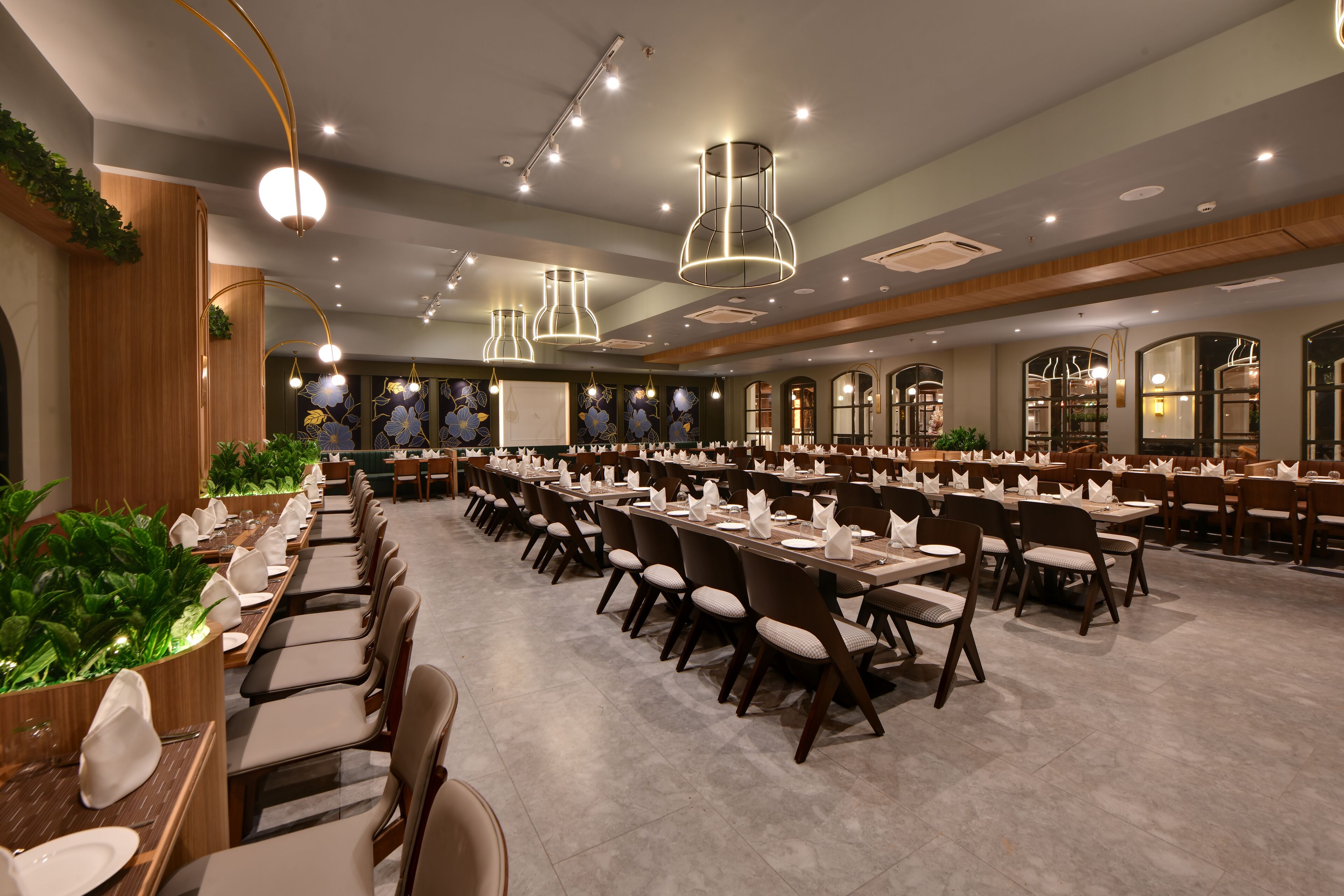 A spacious dining area with long tables, chairs, and modern lighting fixtures.