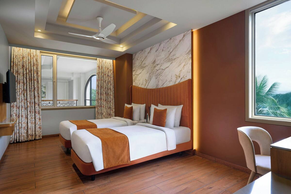 Ein Hotelzimmer mit zwei Betten, einem Deckenventilator, einem großen Fenster mit Blick und Holzboden.