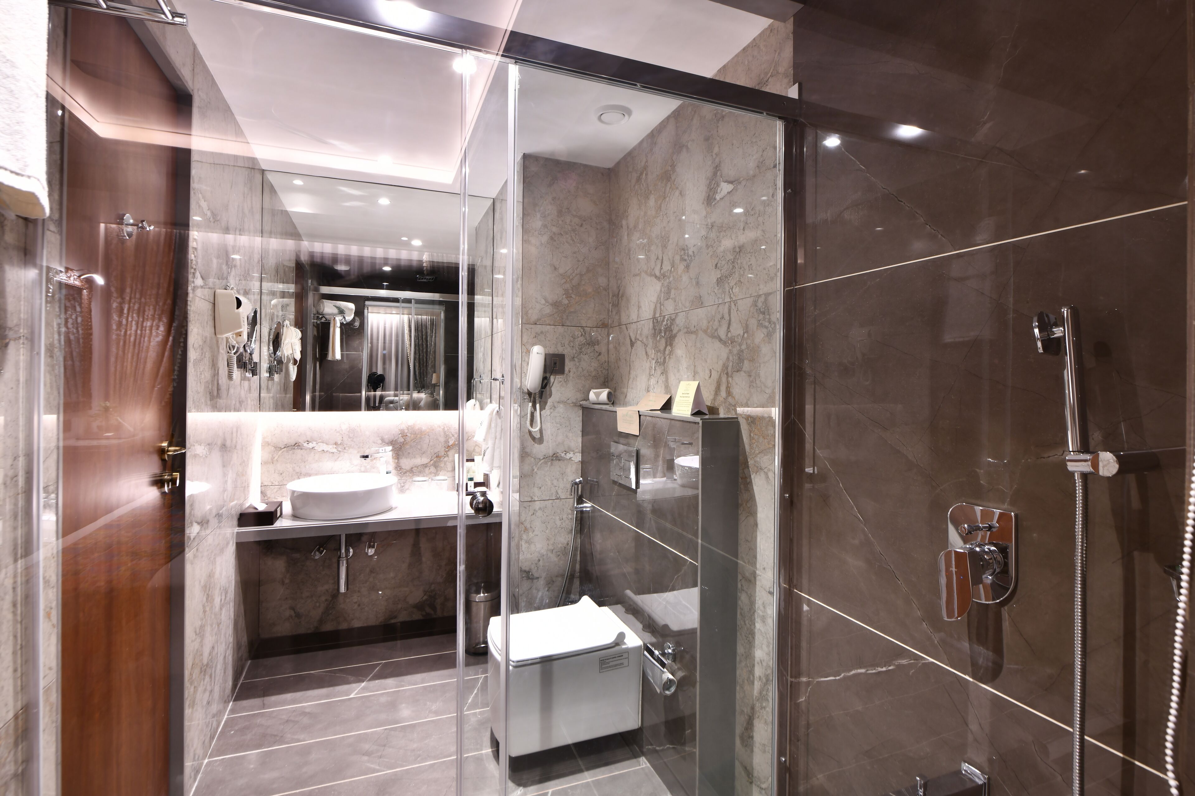 Un baño moderno con ducha de vidrio, tocador con lavabo y un inodoro.