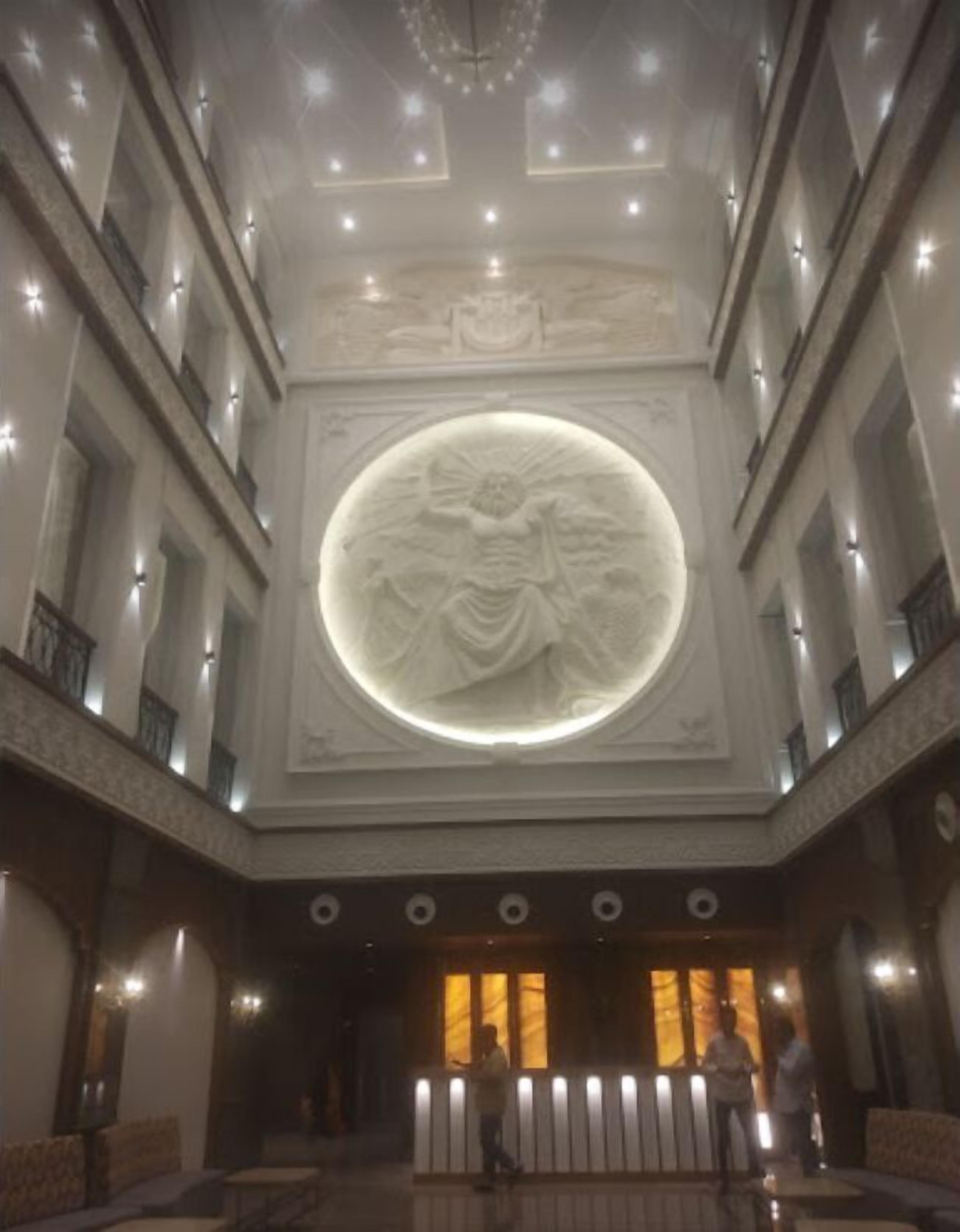 Un vaste hall d’entrée orné d’un grand relief circulaire, de nombreux balcons et d’un lustre.