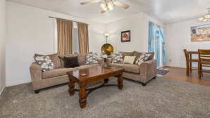 Ein Wohnzimmer mit zwei Sofas, einem Couchtisch, einem Deckenventilator und einem Essbereich mit Tisch und Stühlen.