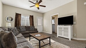 Ein Wohnzimmer mit einer Couch, einem Couchtisch, einem Deckenventilator, einem Fernseher und einem Schrank.