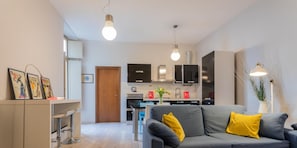 Ein modernes Wohnzimmer mit einem grauen Sofa, gelben Kissen und einem Essbereich mit Tisch und Stühlen.