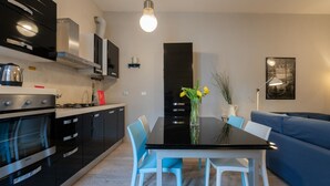 A modern kitchen with black cabinets, a stainless steel oven, and a black dining table with white chairs. - La Maison du Vent by Wonderful Italy (Turin)