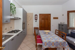 Eine kleine Küche mit Gasherd, Backofen und einem Esstisch mit Stühlen.