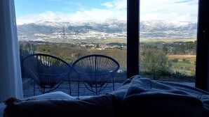 A room with a bed and two chairs facing a mountain view. - Villa Regadio (Covilhã)