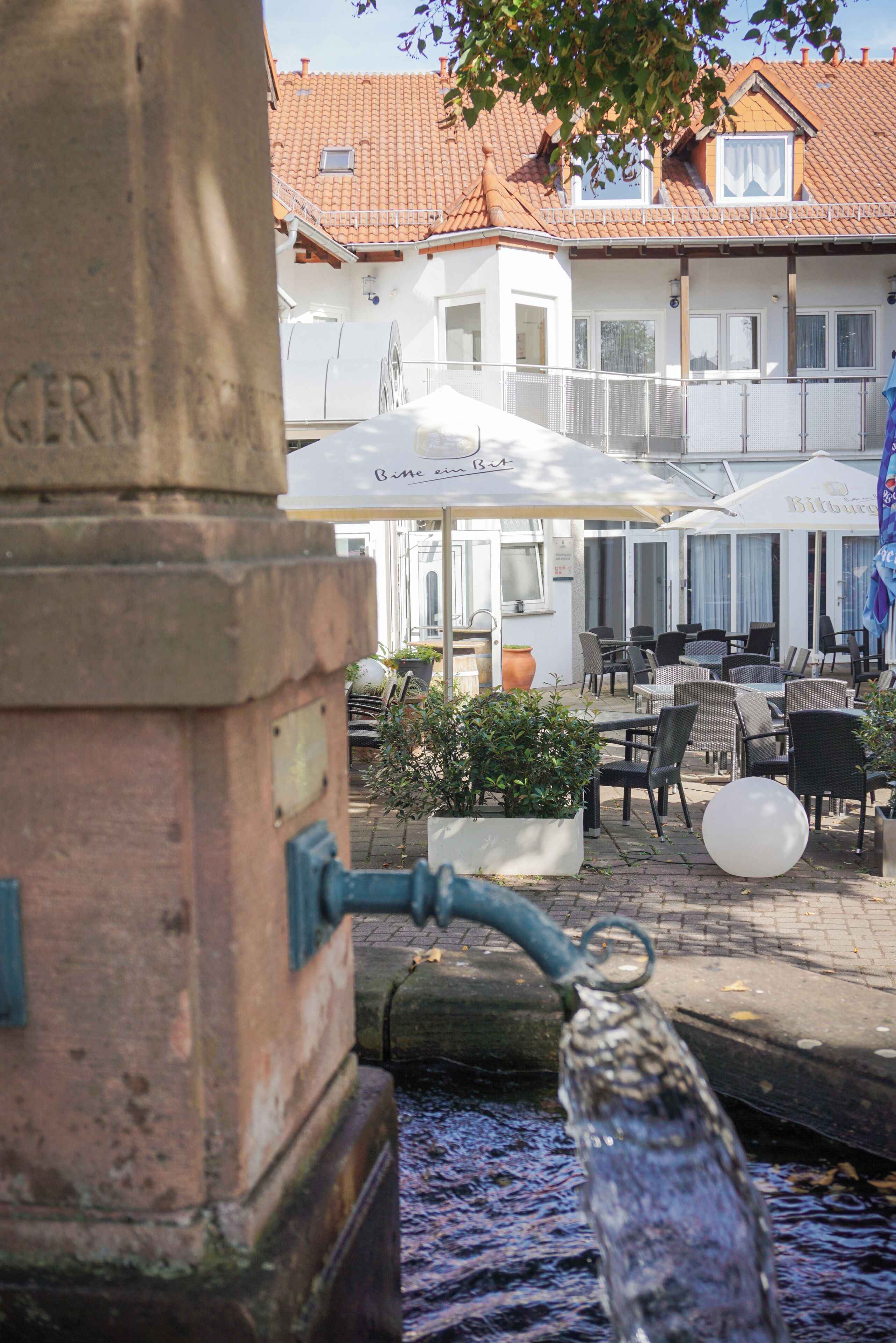 A water spout, outdoor seating, and a building with a tiled roof.