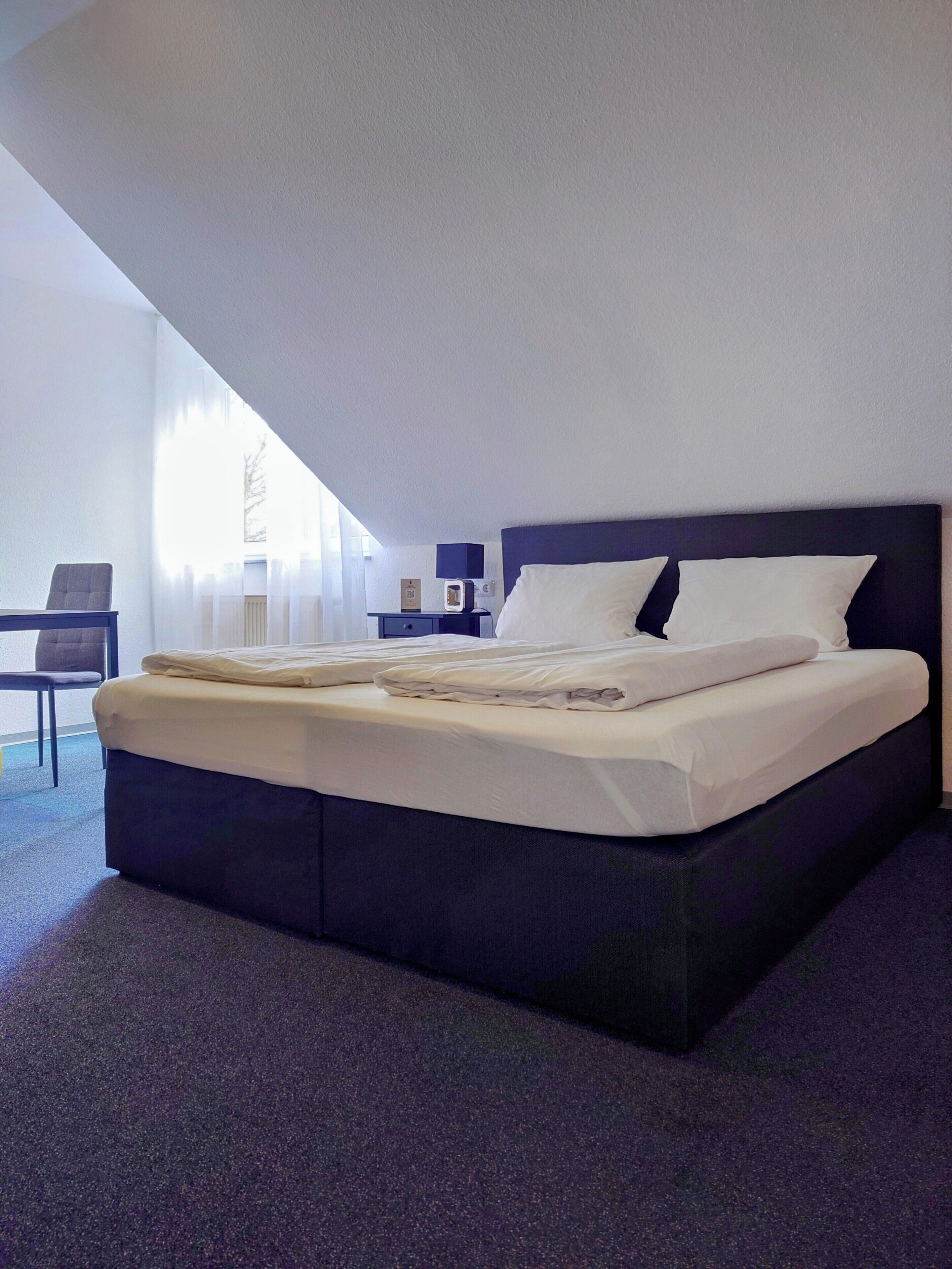 Una habitación de hotel moderna con una cama grande, un escritorio y una silla.