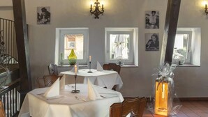 A dining area with wooden beams, white tablecloths, and candle holders. - Hotel Schlemmerscheune (Weilerbach)