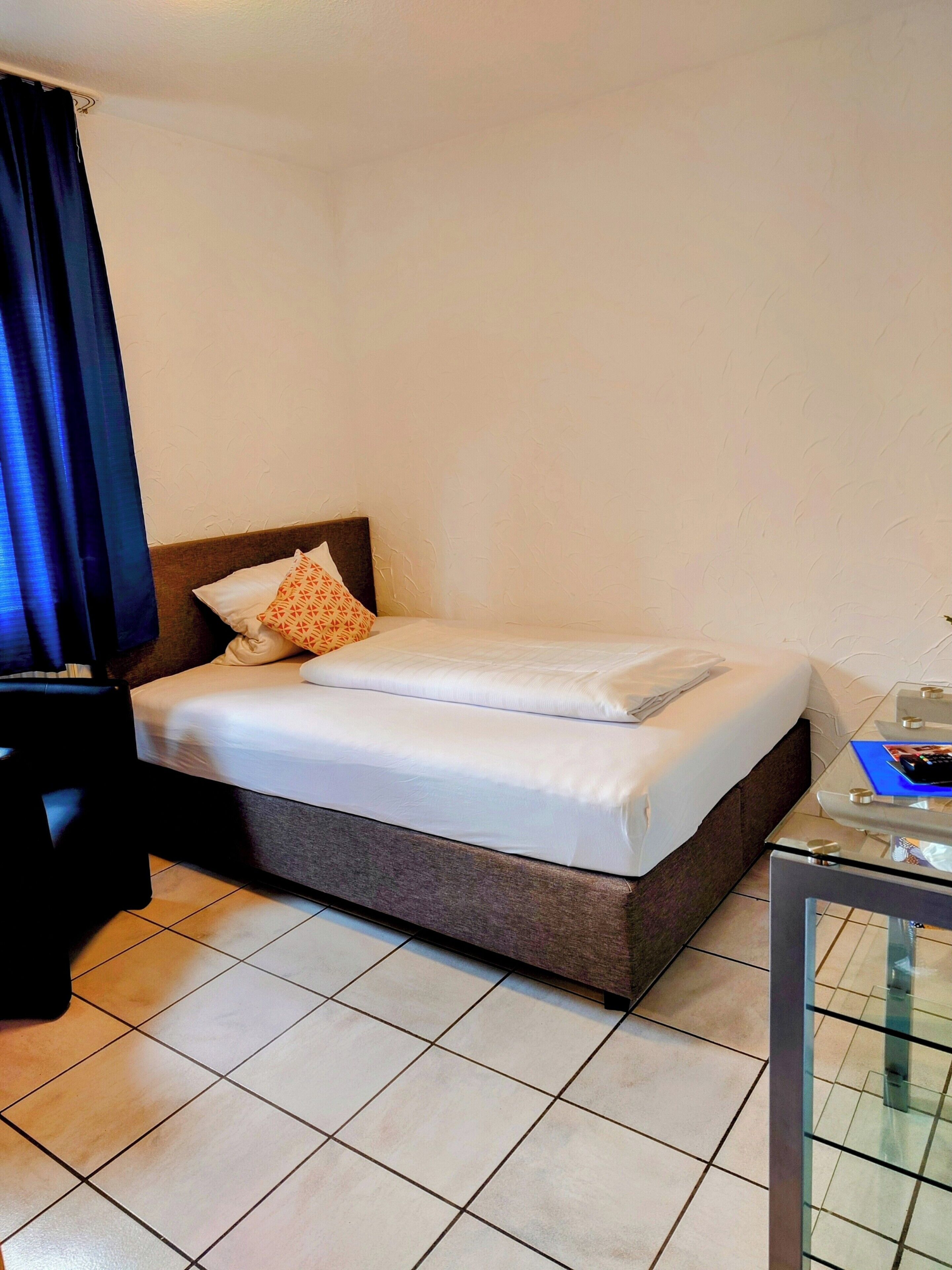 A hotel room with a bed, a glass table, and a chair.
