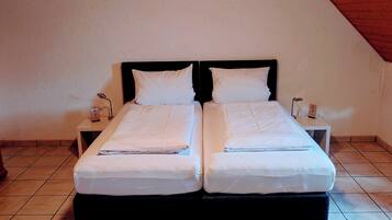 A double bed in a room with a sloped ceiling and tiled floor.