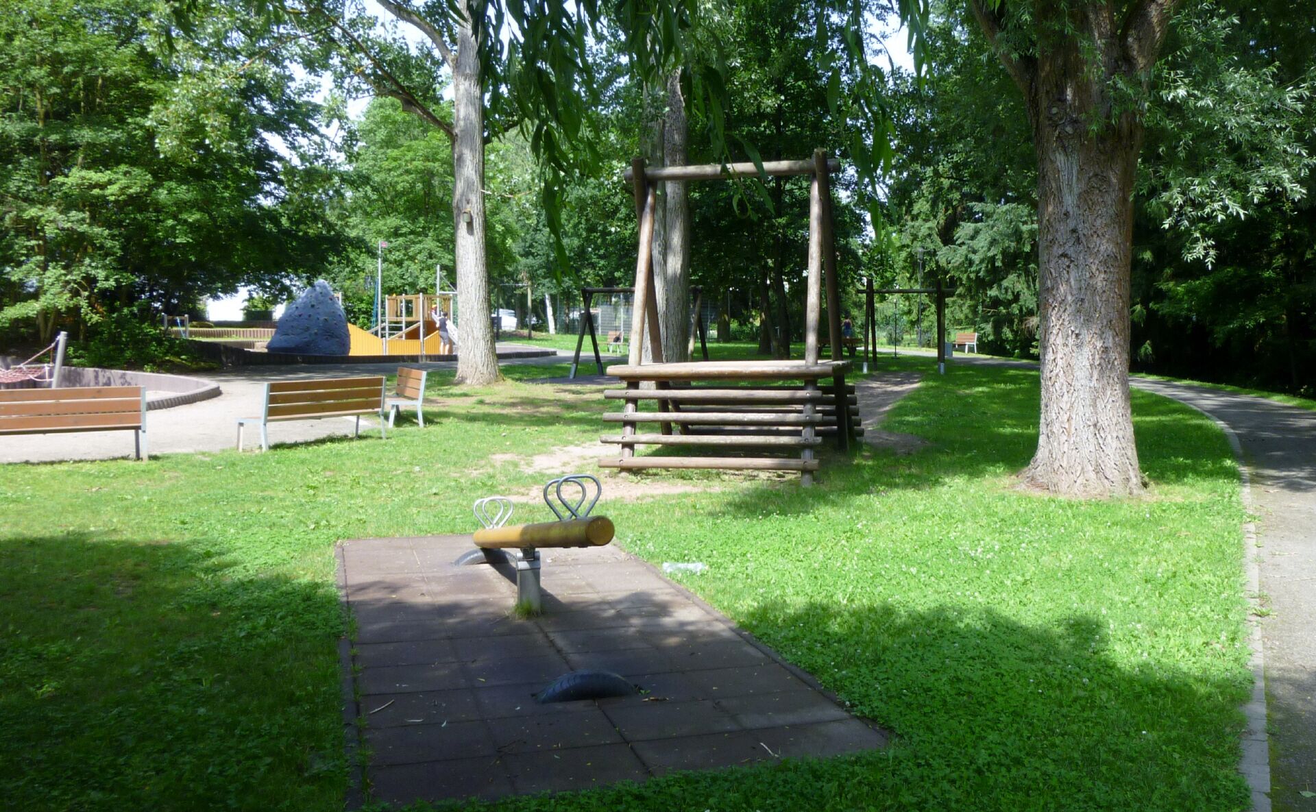 A park with a swing set, benches, and a playground.
