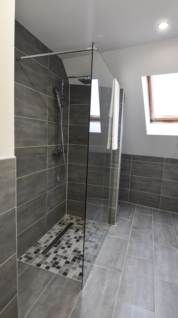 A walk-in shower with a glass door, tiled walls, and a small window. - Hotel Schlemmerscheune (Weilerbach)