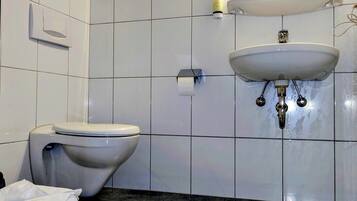 Kylpyhuone, jossa on wc, pesuallas ja pyyheteline.