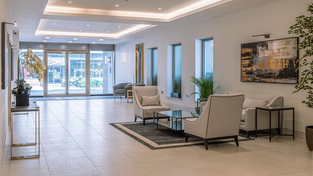 A modern lobby with a reception desk, seating area, large windows, and a view of the outside. - Apartment 107 - A premium stay that sleeps 4 guests  in 2 bedrooms (York)