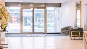 A modern reception area with a glass door entrance, a reception desk, and a seating area with a sofa and chairs. - Apartment 107 - A premium stay that sleeps 4 guests  in 2 bedrooms (York)