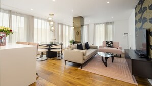 A modern living room with a sofa, coffee table, and dining area. - Apartment 107 - A premium stay that sleeps 4 guests  in 2 bedrooms (York)