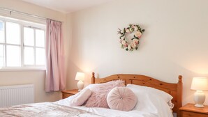 Une chambre à coucher comprenant un lit, deux tables de chevet, une fenêtre avec des rideaux et un élément décoratif mural.