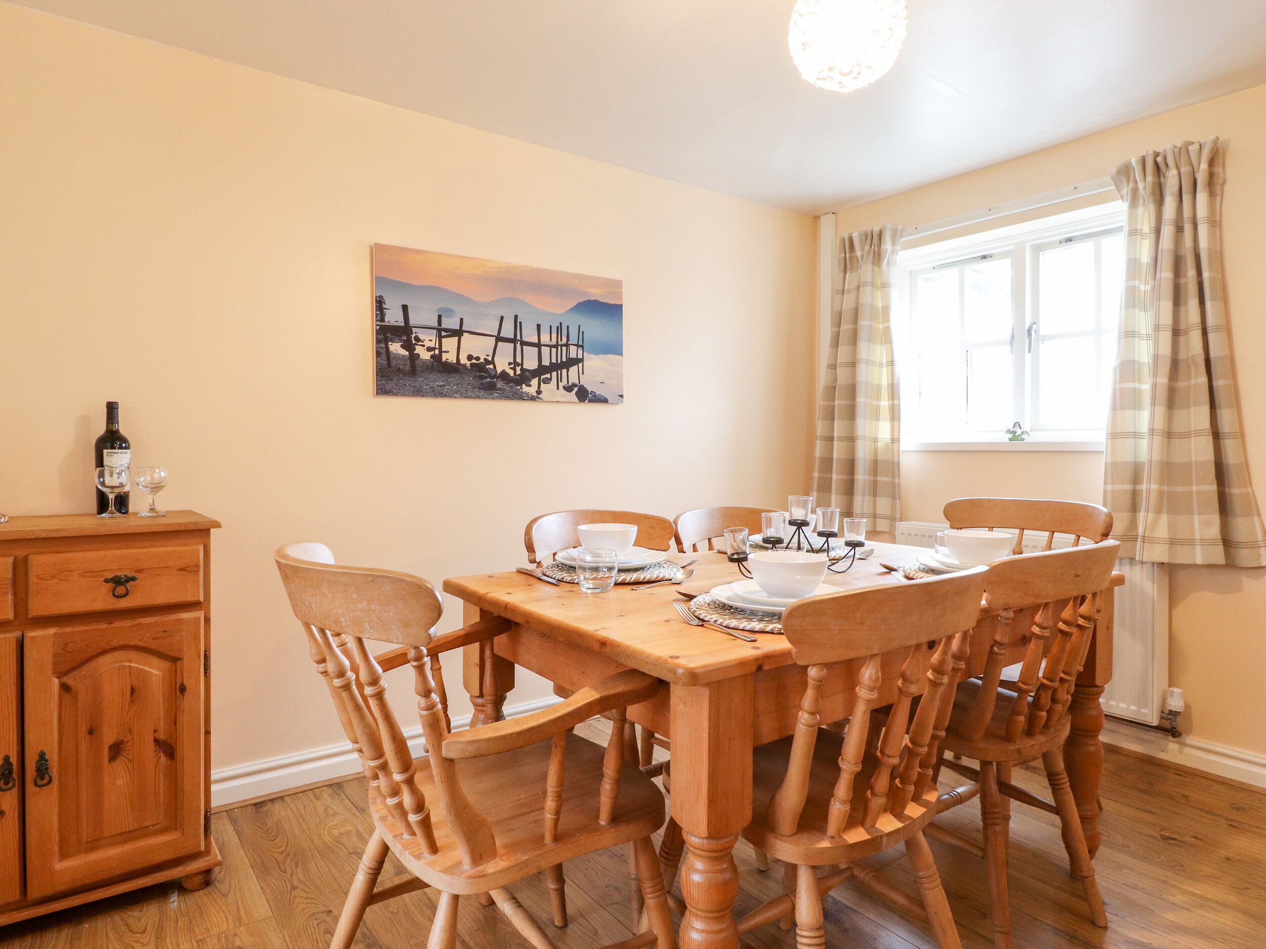 Un coin repas avec une table en bois, des chaises, un buffet et un tableau accroché au mur.