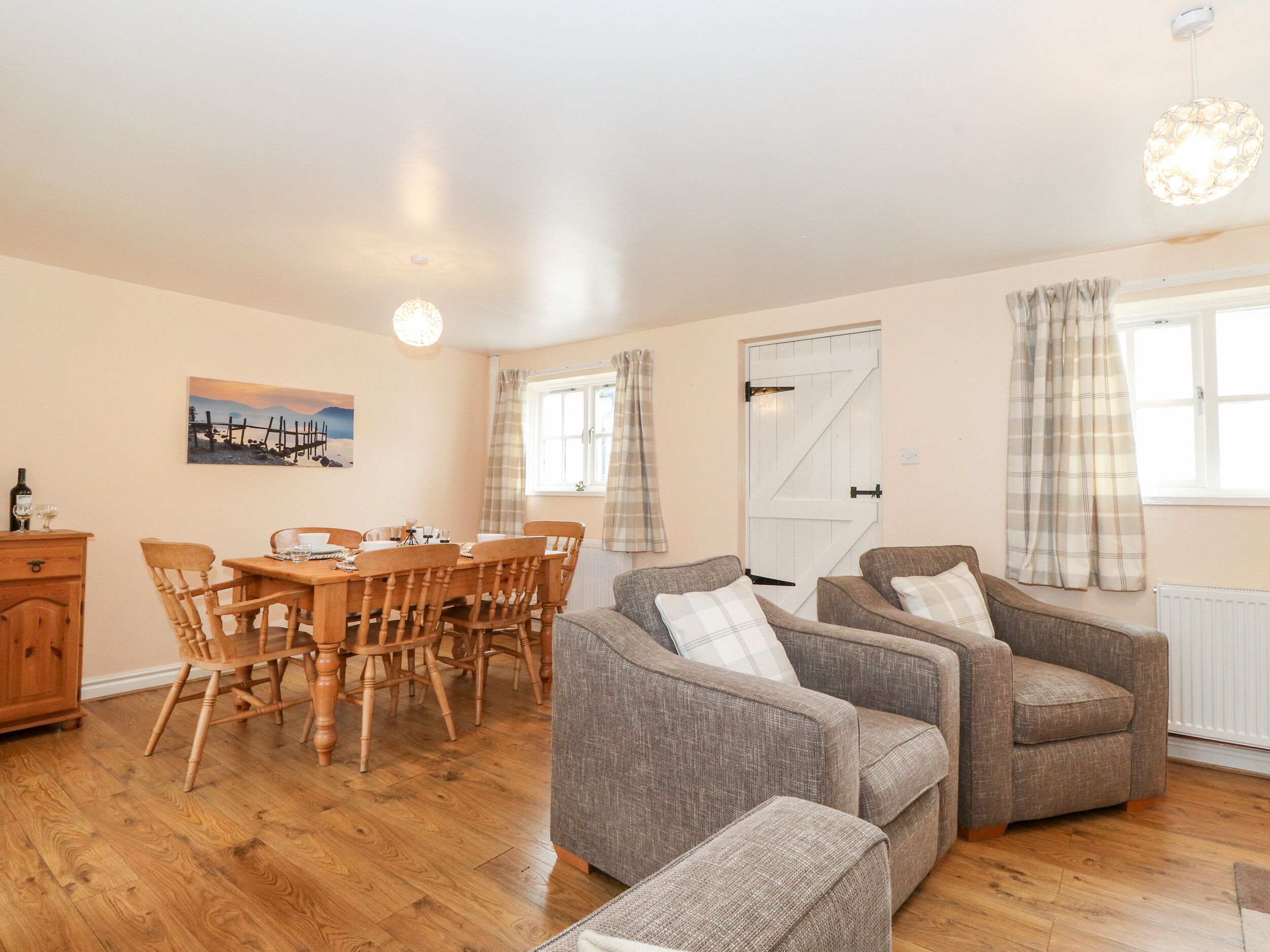 A cozy living room with a wooden dining table, two armchairs, and a sofa.