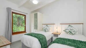 A bedroom with two beds, a window with curtains, a cabinet, and a bedside table with a lamp. - San Lameer Villa 2705 (Southbroom)