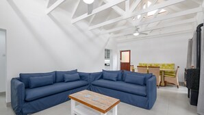 A modern living room with a blue sectional sofa, a wooden coffee table, and a dining area with a table and chairs. - San Lameer Villa 2705 (Southbroom)