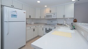 A modern kitchen with white cabinets, a refrigerator, a microwave, an oven, and a sink. - Casa Del Mare, beautiful 3 BD /3 Bathroom condo just steps to the beach, walking distance to activities. (Ocean City)