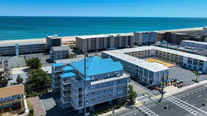 A multi-story hotel with a blue roof, located near a beach with a clear view of the ocean. - Casa Del Mare, beautiful 3 BD /3 Bathroom condo just steps to the beach, walking distance to activities. (Ocean City)