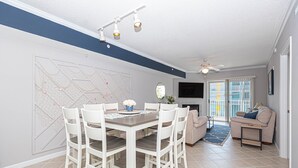 A dining area with a white table and chairs, a map on the wall, a ceiling fan, and a sofa in the background. - Casa Del Mare, beautiful 3 BD /3 Bathroom condo just steps to the beach, walking distance to activities. (Ocean City)