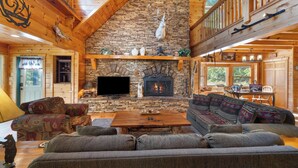 Un interior de cabaña acogedor con chimenea de piedra, vigas de madera y una zona de estar cómoda.