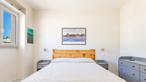 A bedroom with a wooden headboard, a bed with a white quilt, a nightstand, a dresser, and a framed picture on the wall. - 3233 Villa Lucechiara by Barbarhouse (Avetrana)