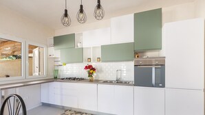A modern kitchen with white and green cabinets, a gas stove, a sink, and pendant lights. - 3233 Villa Lucechiara by Barbarhouse (Avetrana)