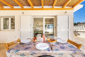 An outdoor dining area with a table set for two, a bottle of rosé wine, and a pitcher of water.