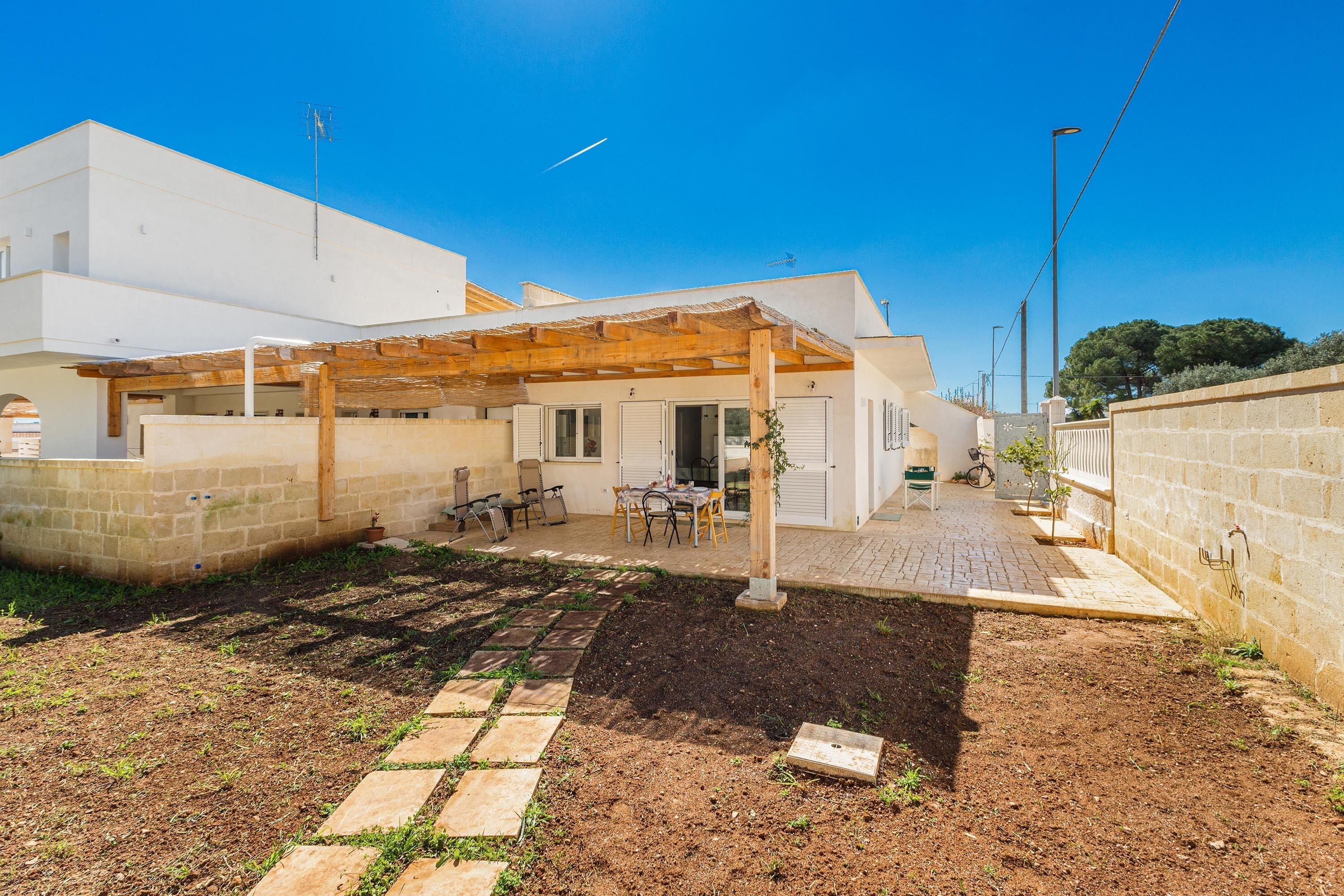 Ein modernes Haus mit überdachter Terrasse, einem Garten mit trittfesten Steinen und einer gepflasterten Auffahrt.