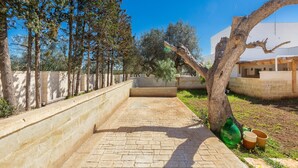 A paved courtyard with a stone wall, trees, and a building with a modern design. - 3233 Villa Lucechiara by Barbarhouse (Avetrana)