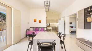 A modern kitchen with white cabinets, a central island, and a dining area with a table and chairs. - 3230 Villino Dalila by Barbarhouse (Maruggio)