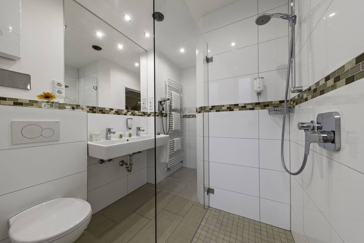 Une salle de bain moderne avec une douche à parois de verre, un lavabo blanc et des toilettes.