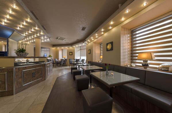 A modern restaurant with a long counter, booths, and a bar area.