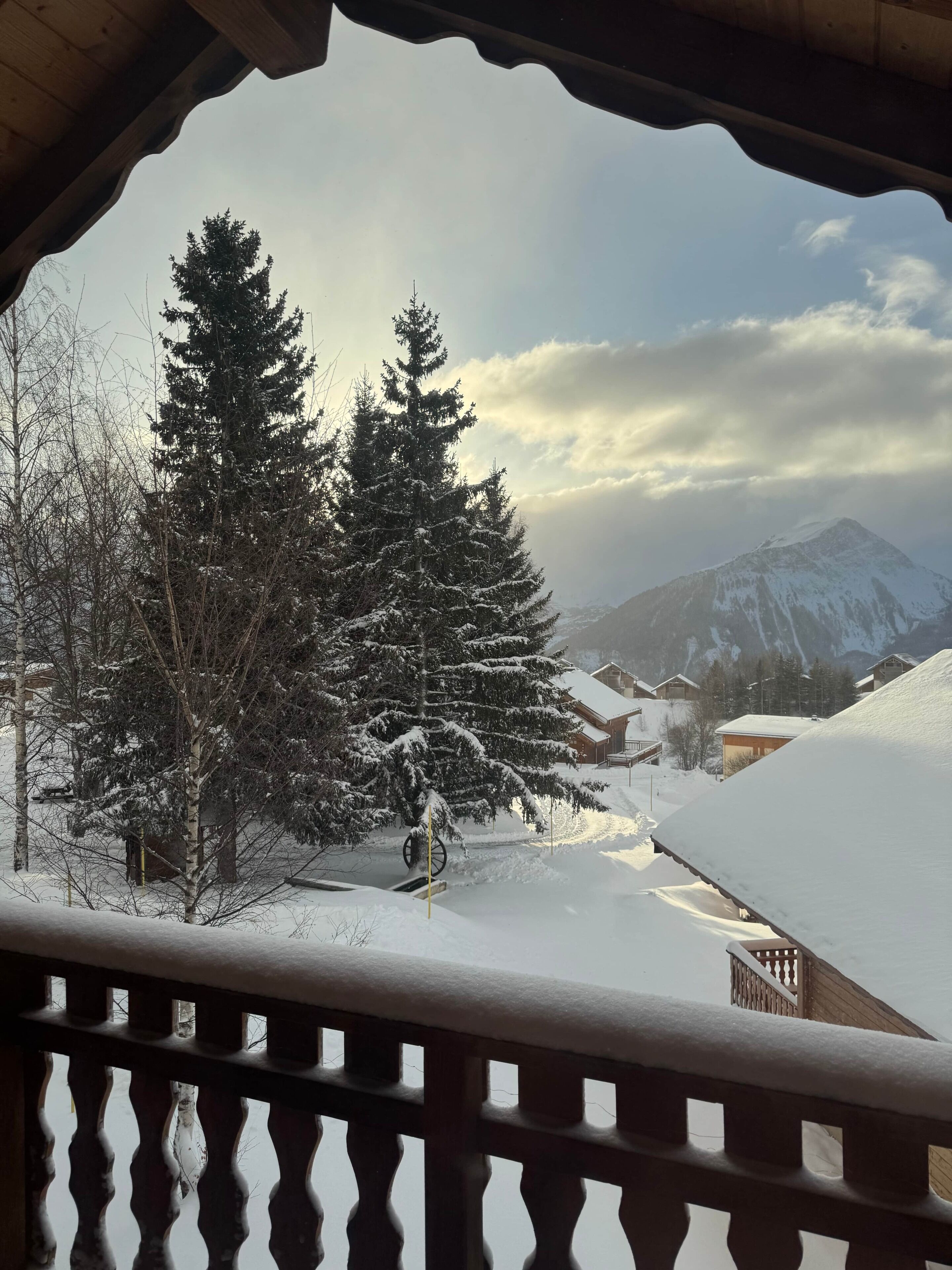 A snowy mountain landscape with a wooden balcony railing.