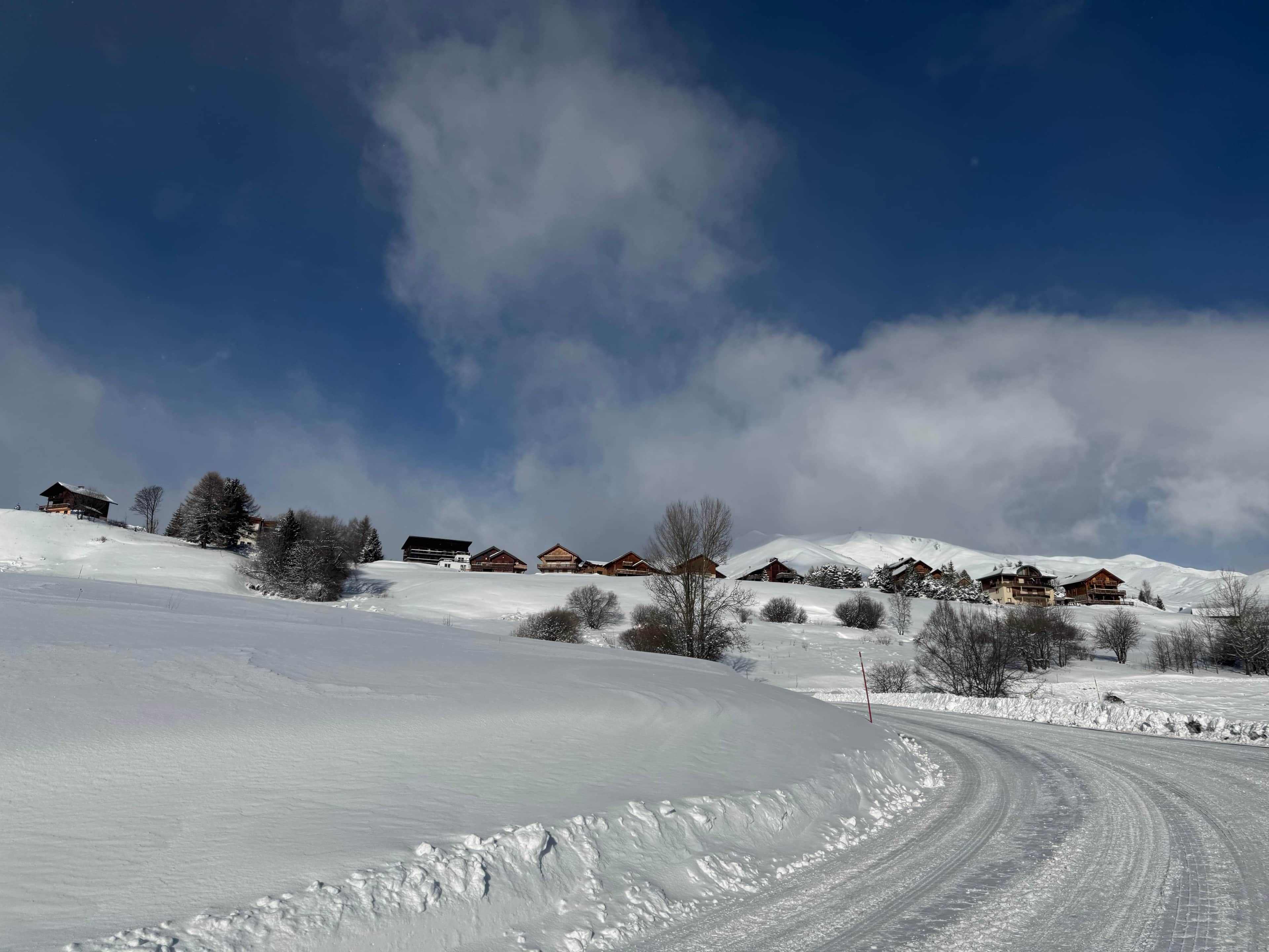 A snow-covered landscape with wooden cabins and a clear sky.