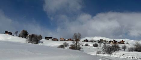 A snow-covered landscape with wooden cabins and a clear sky.