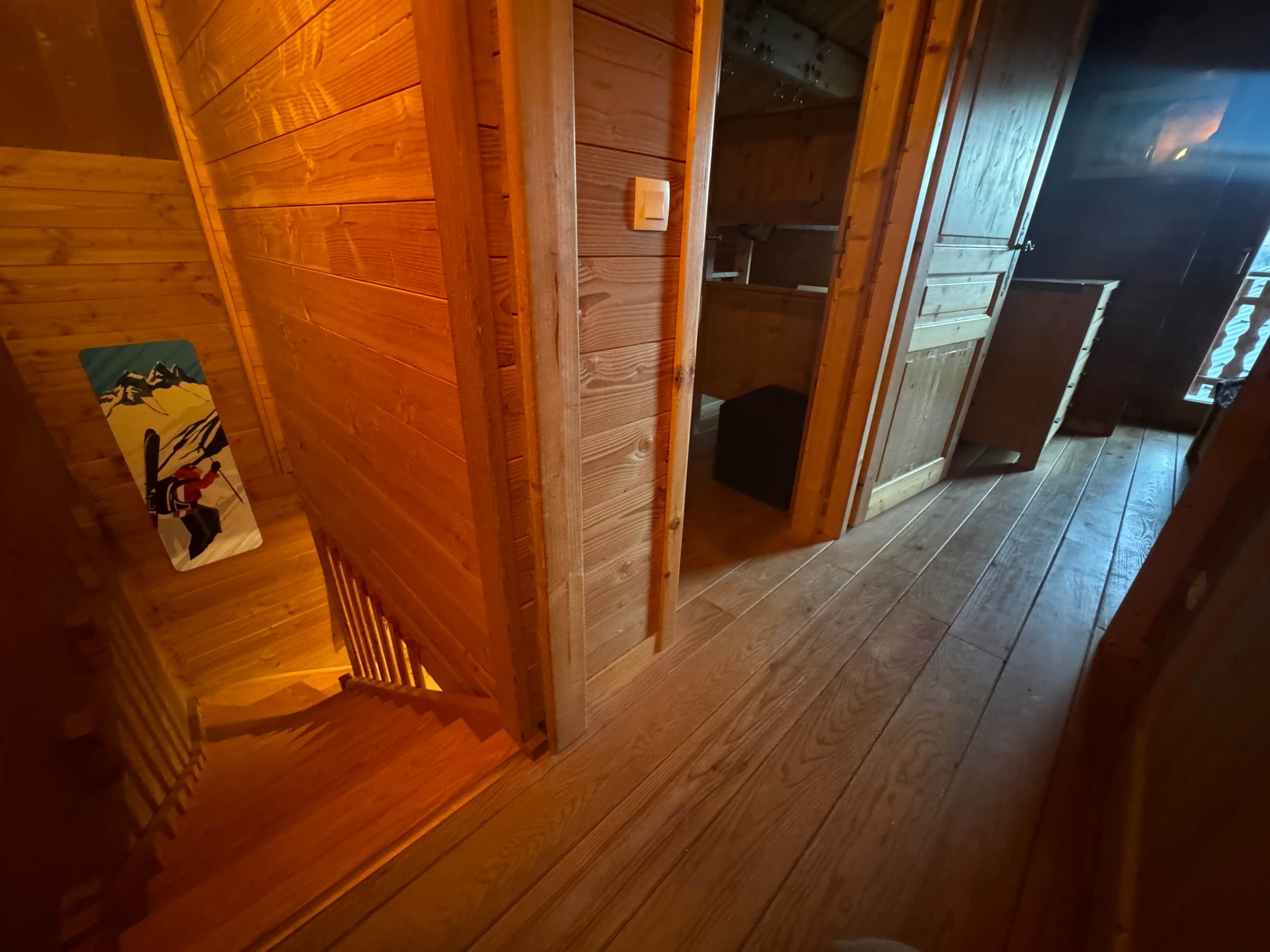 Een houten hal met een houten deur die naar een badkamer leidt.