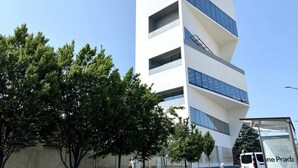 Un bâtiment moderne à la façade blanche et aux touches de bleu, doté de nombreux balcons et de grandes fenêtres.
