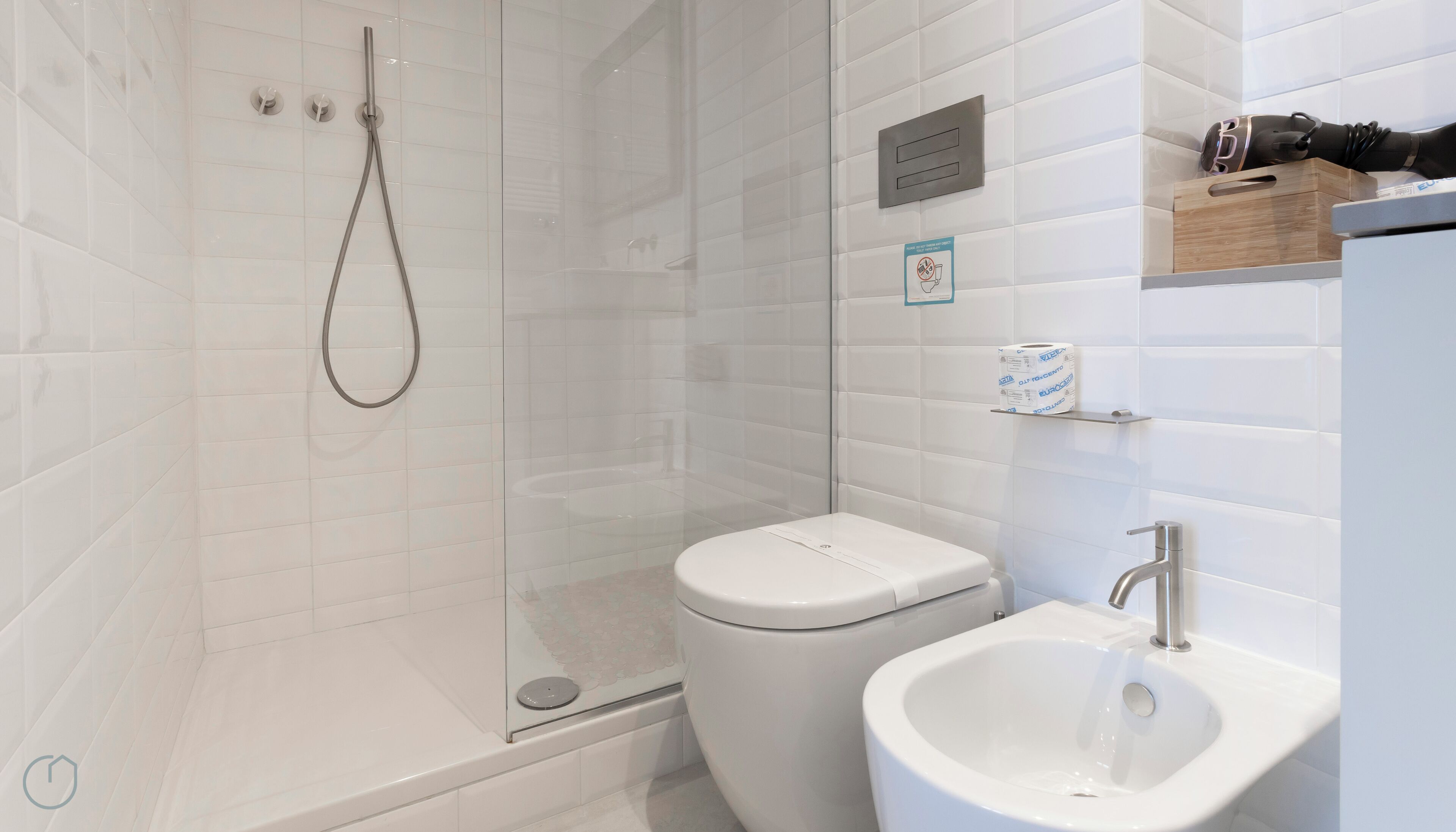 A modern bathroom with a glass-enclosed shower, a toilet, and a sink.