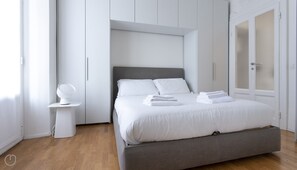 Relax in a serene space with a neatly made bed, bedside table, and wardrobe.